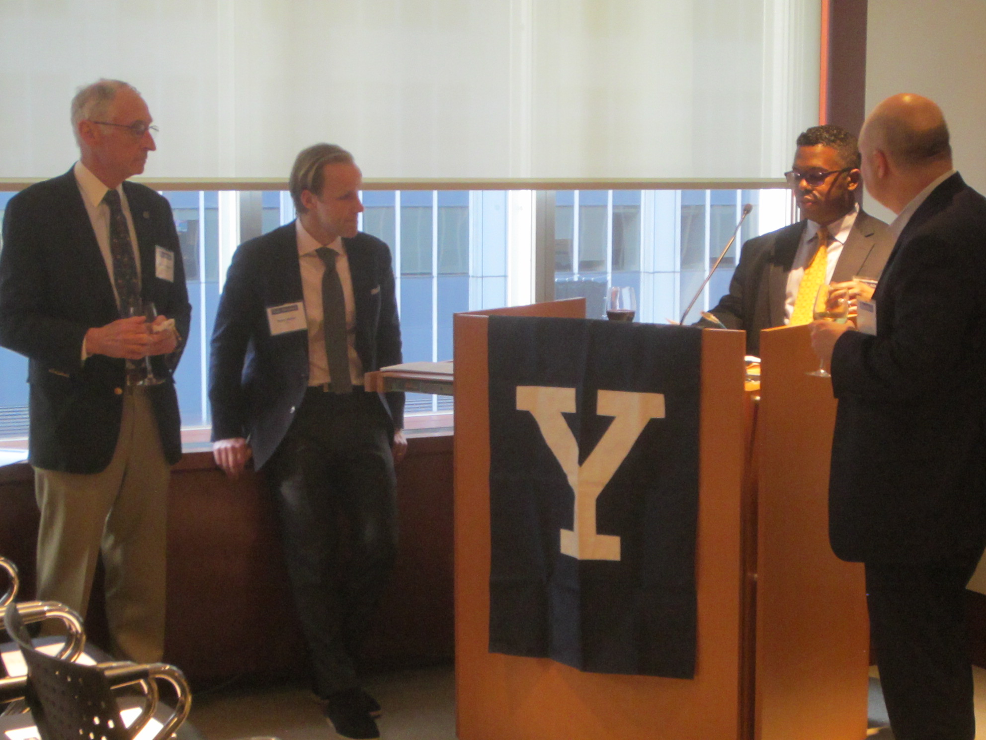 Sulexan Chery ’15 MBA, YaleFin co-chair, delivers opening remarks at the Impact Investing program. He is joined by fellow co-chairs, Tom Opladen ’66 (left) and Neil Hohmann ’91 (right), and program co-moderator Ross Mellor ’08 MBA. Photo: Henry Kwan