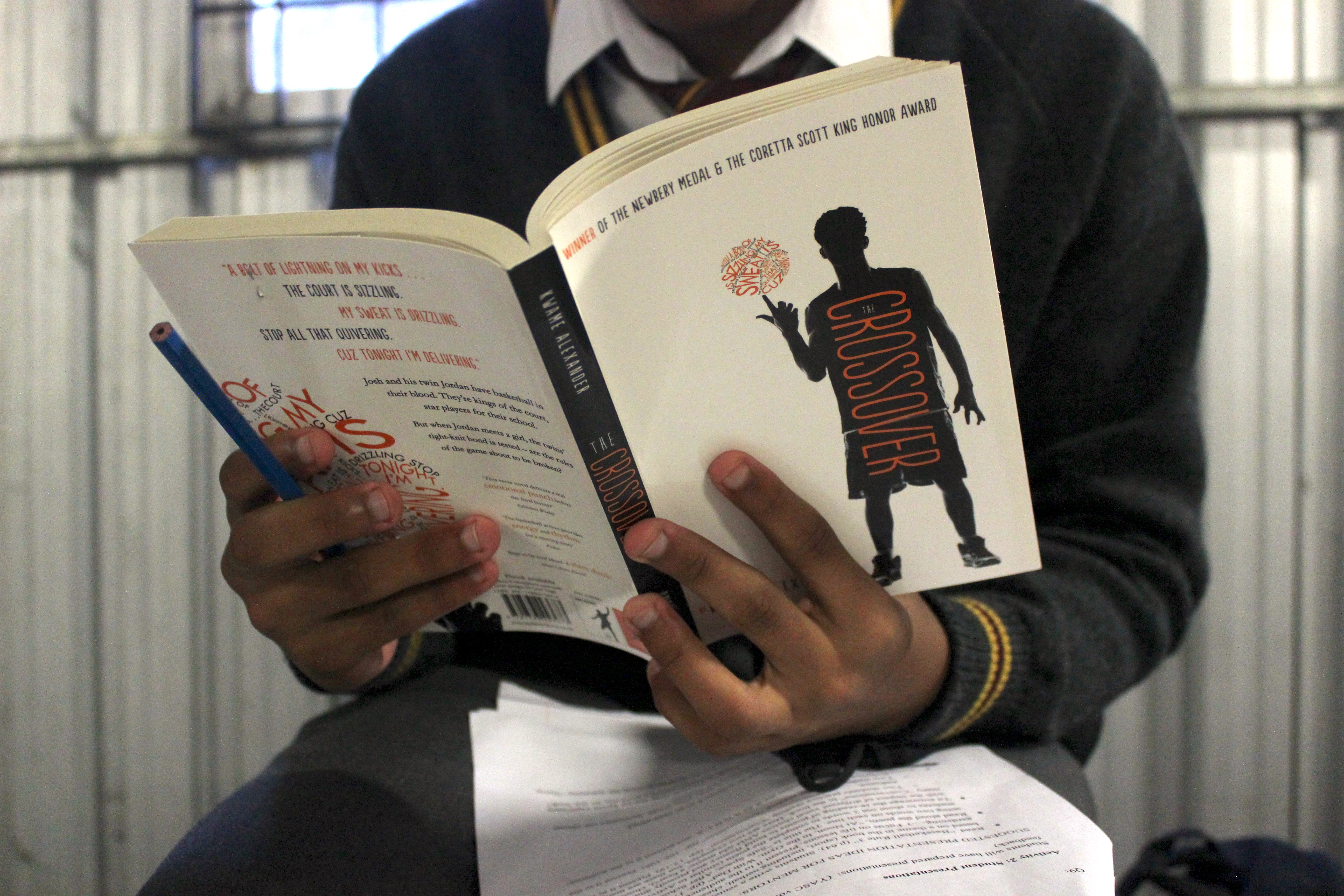 A student holds a book from the "Crossover" series.