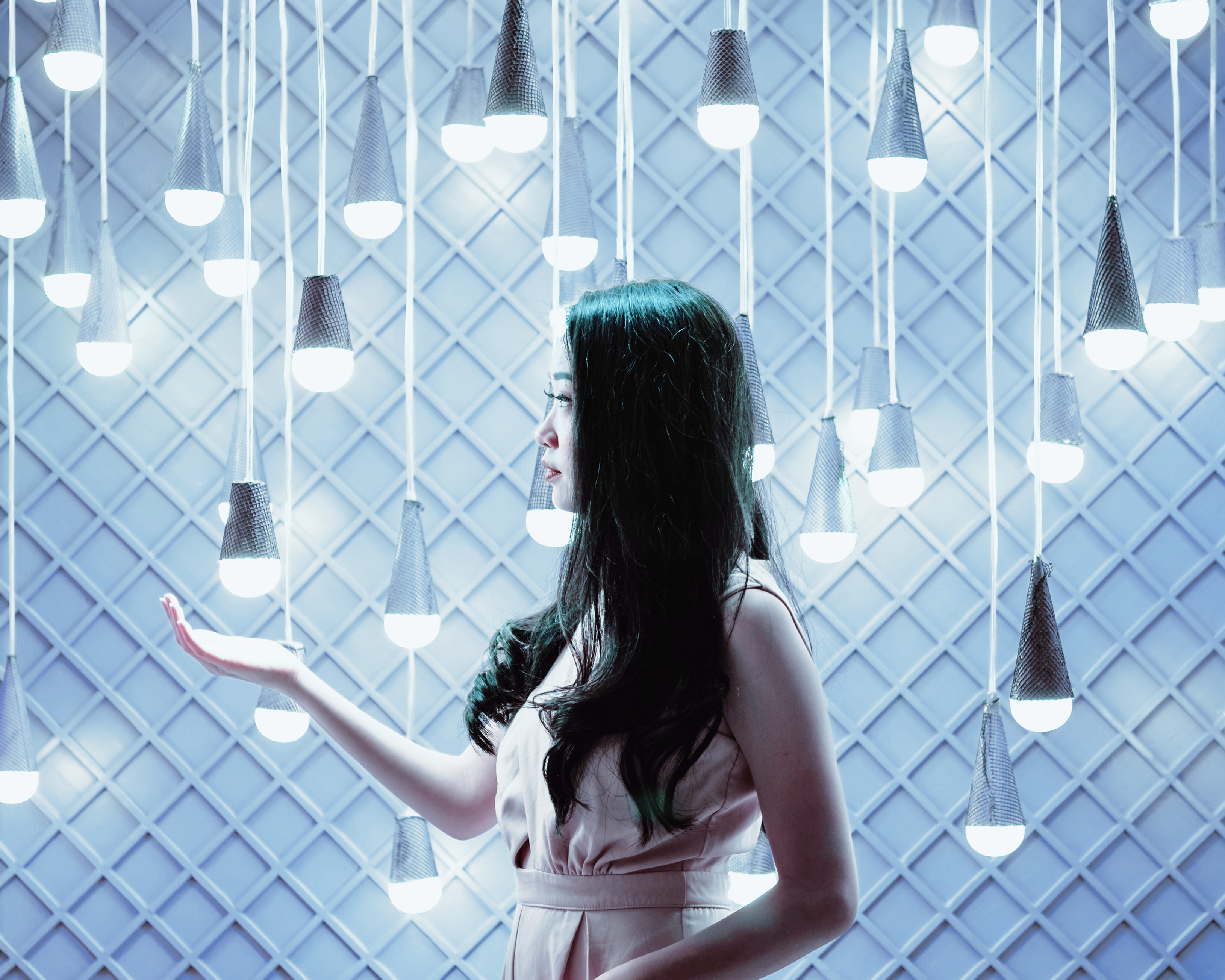 Woman standing in front of a wall of hanging lightbulbs