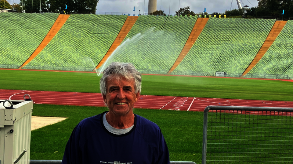 Frank Shorter ’69 standing at Munich Olympic Stadium finish line